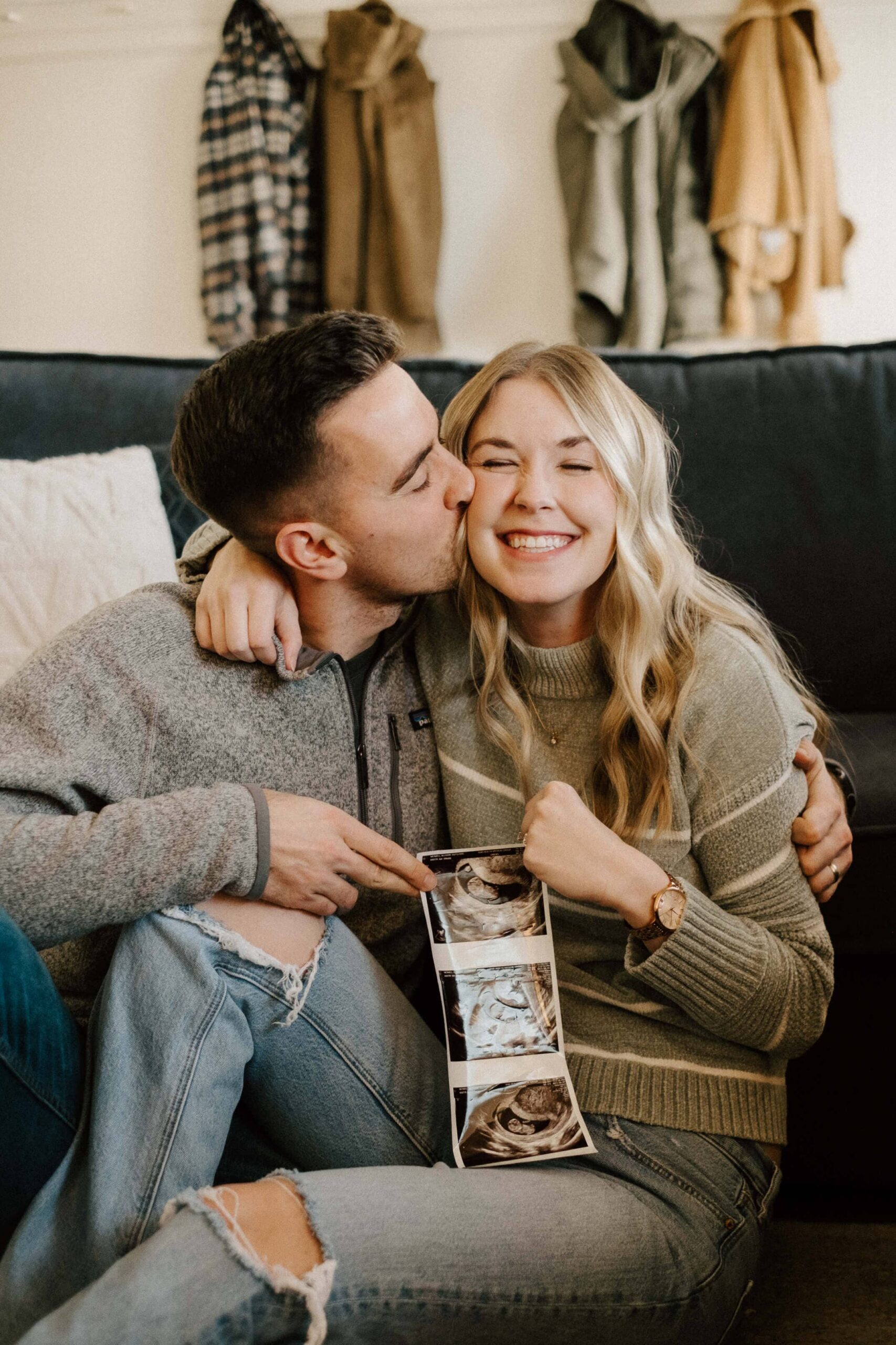 Happy couple showing off their sonogram at their home photoshoot in St. Louis, Missouri, captured with a nostalgic film aesthetic by Stacey Vandas Photography.