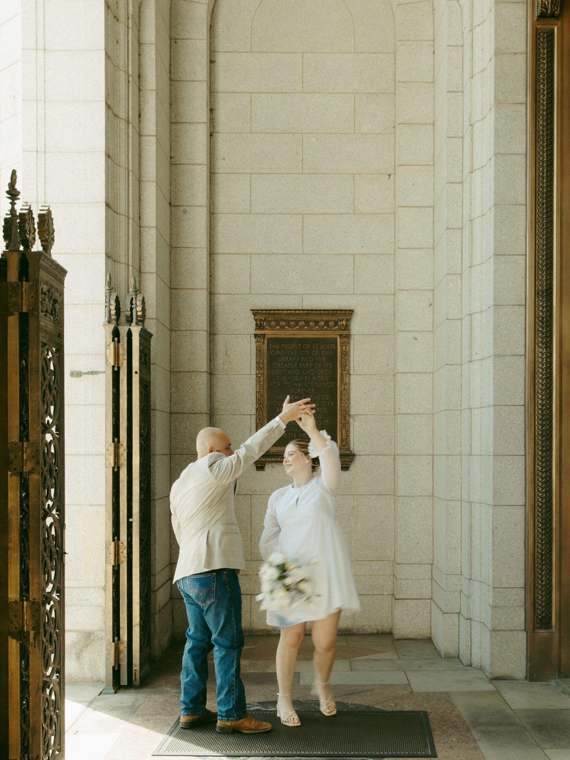 A couple dances in an arched entryway of a historic library during a St. Louis elopement.