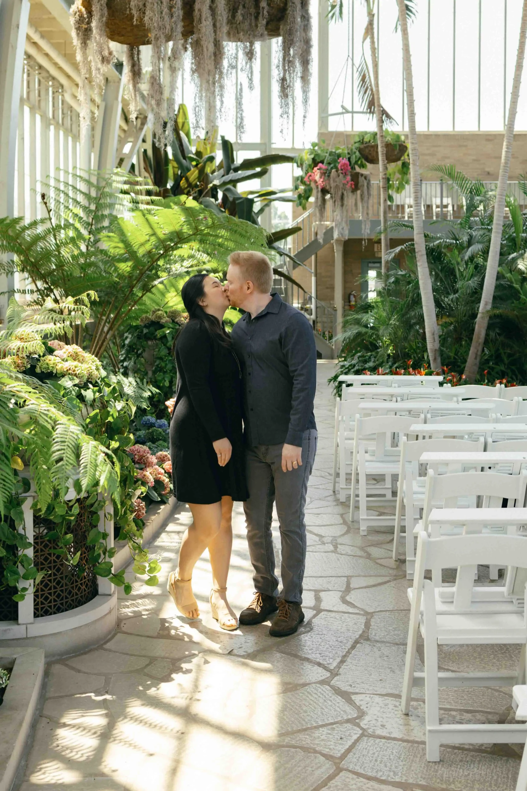 A couple kissing in a sunny greenhouse venue in St. Louis, Missouri.