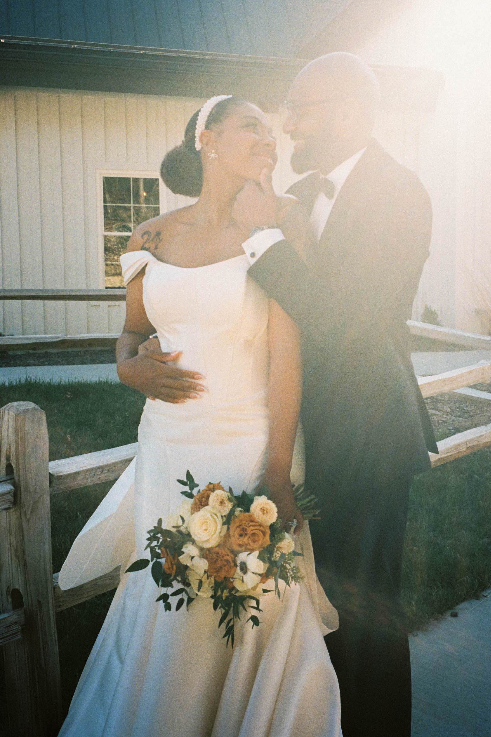 A bride and groom embrace and smile in a documentary-style film photo.