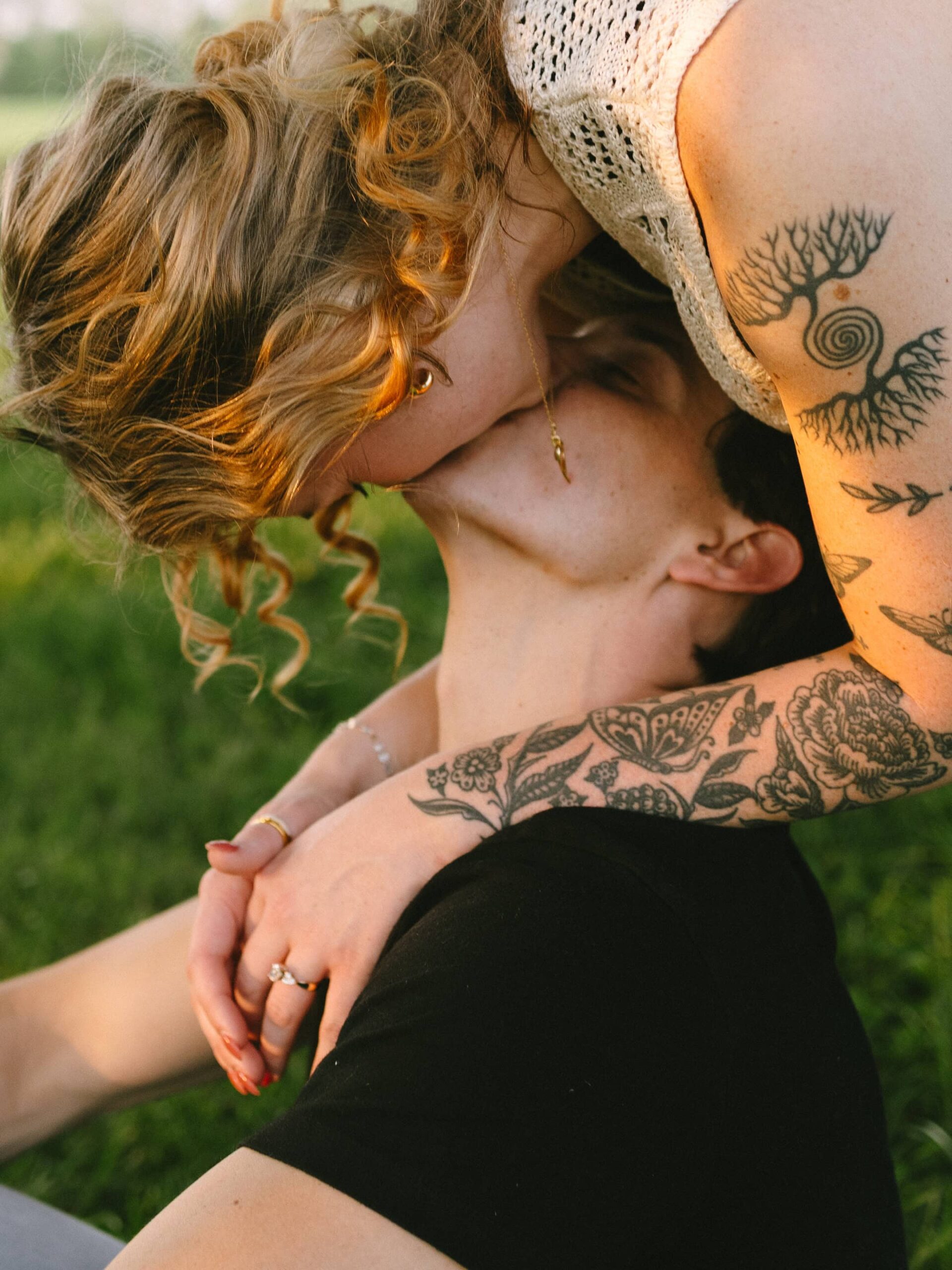 a woman leans over a sitting man and kisses him upside down in golden hour light