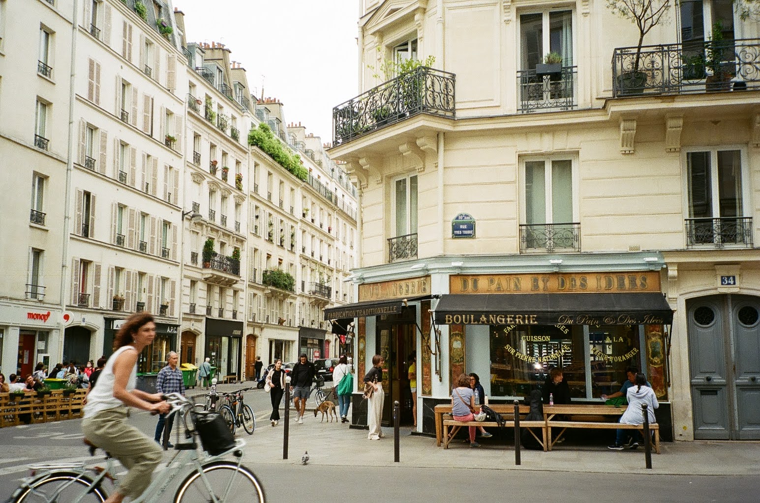 A woman bikes past a bakery in Paris, shot on 35mm film.