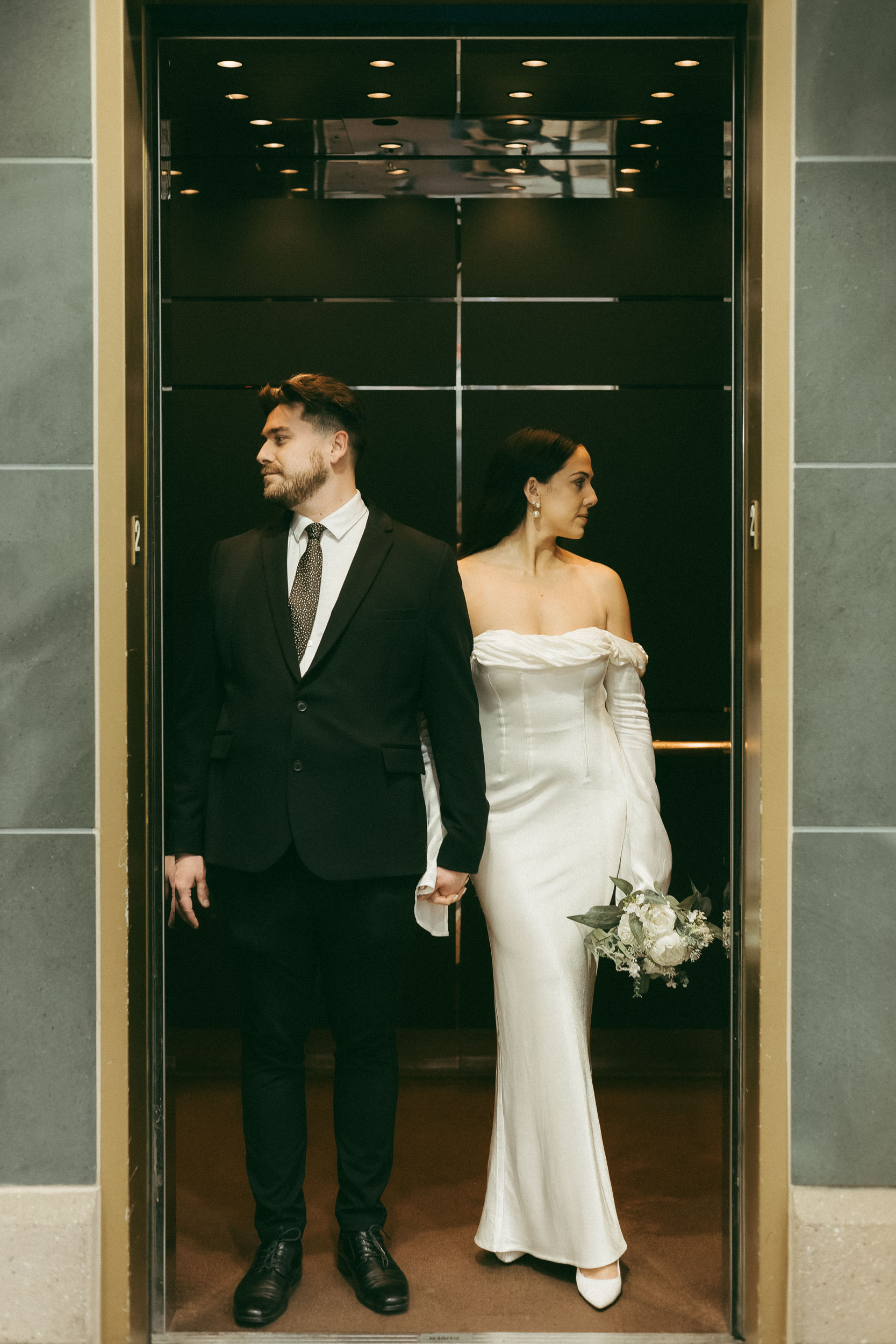 A couple poses in an elevator during an intimate city hall elopement ceremony.