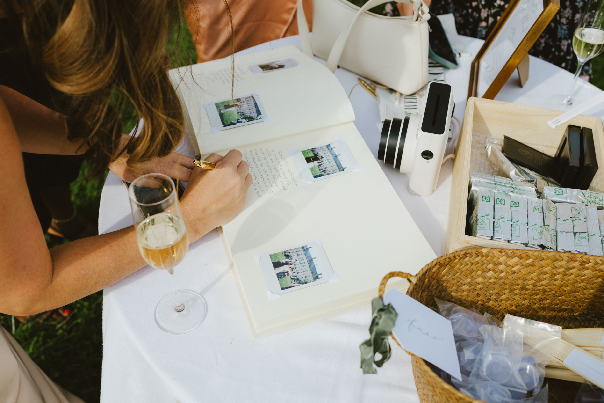 A guest at a wedding fills out a polaroid guest book with a meaningful note.