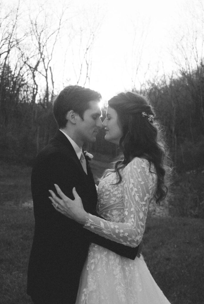 A bride and groom embrace tenderly in a woodsy elopement shot on 35mm black and white film.