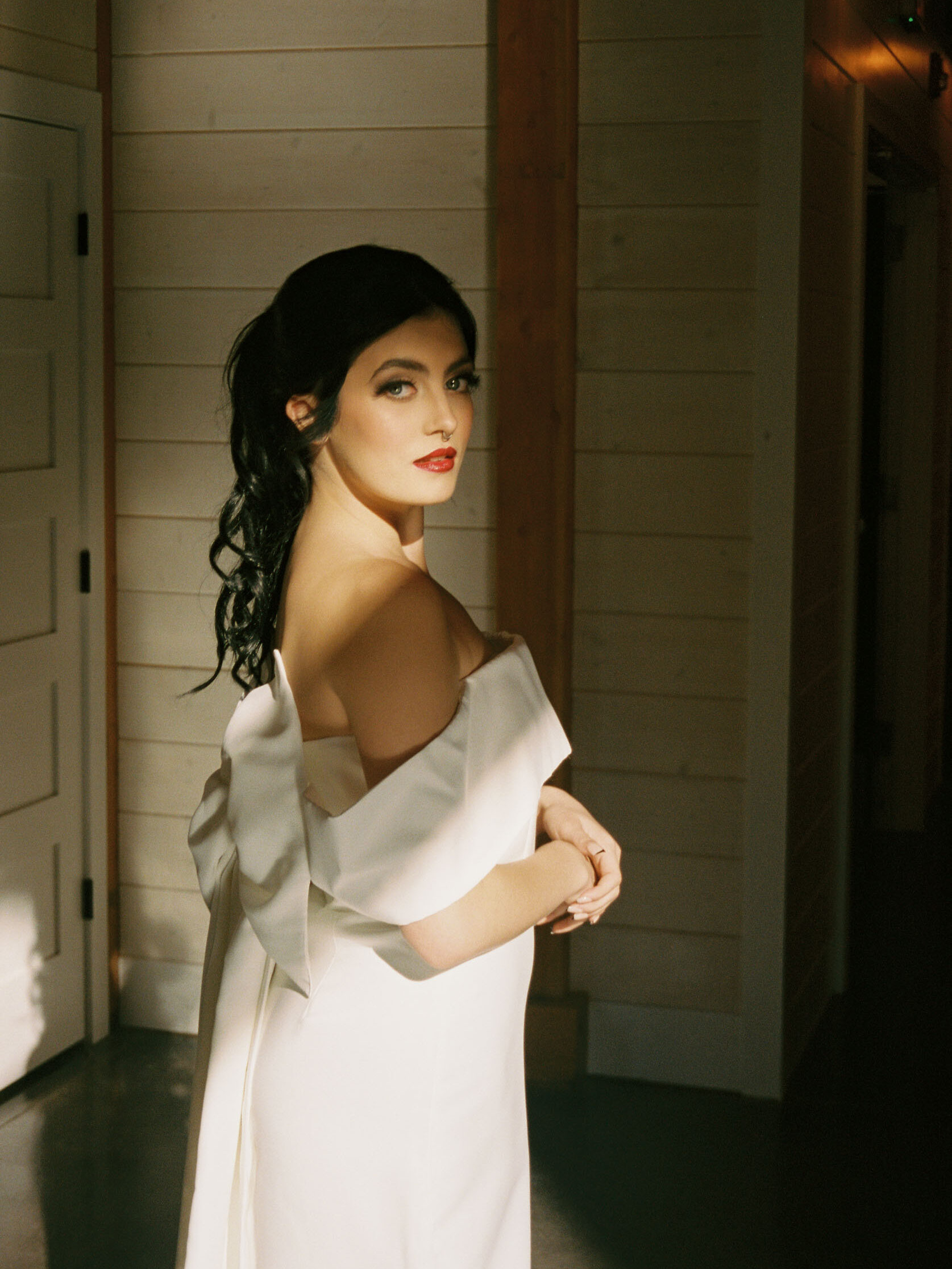 A bride looks over her shoulder in a moody bridal portrait shot on 35mm film by Stacey Vandas.