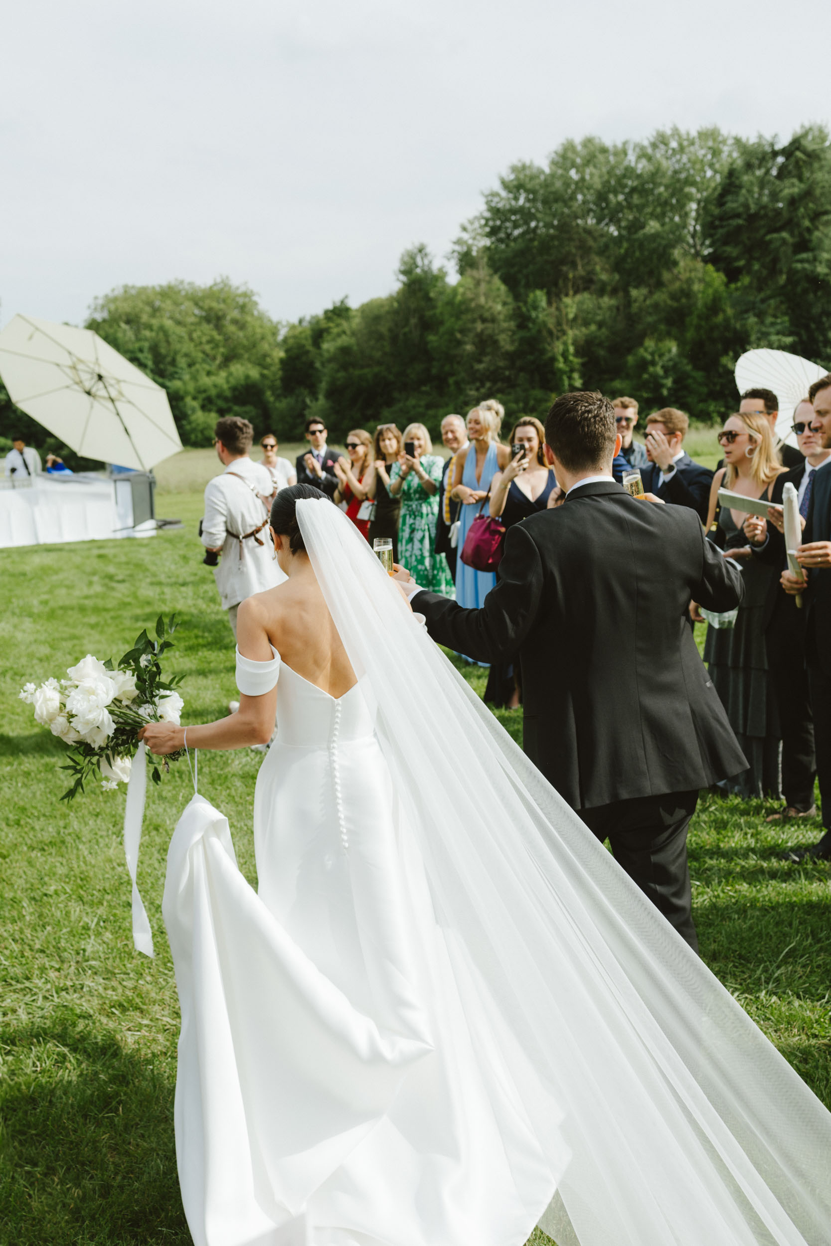 A bride and groom walk through their guests into a cocktail hour, shot with a documentary-style in Paris, France.