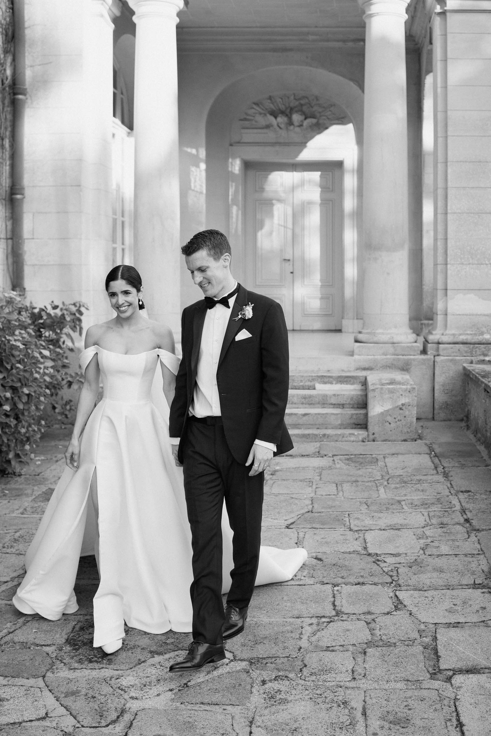 A bride and groom walk together in a documentary-style black and white photo.