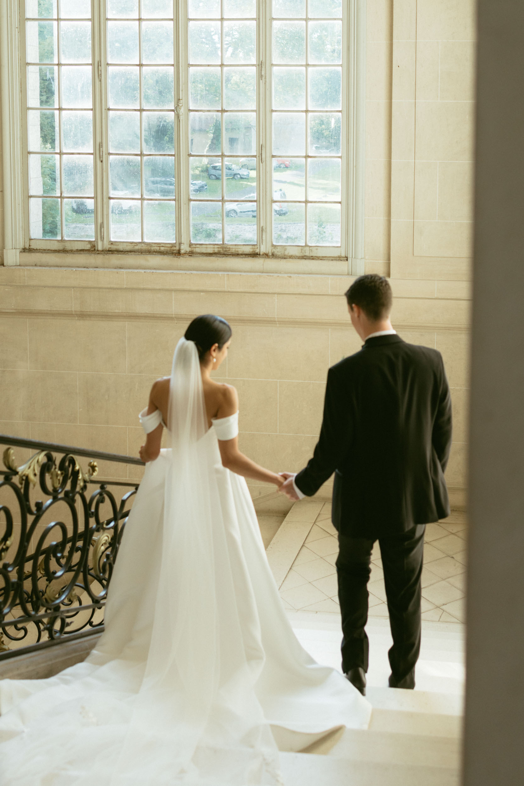 A bride and groom walk down the stairs of a historic chateau in a documentary-style wedding photo