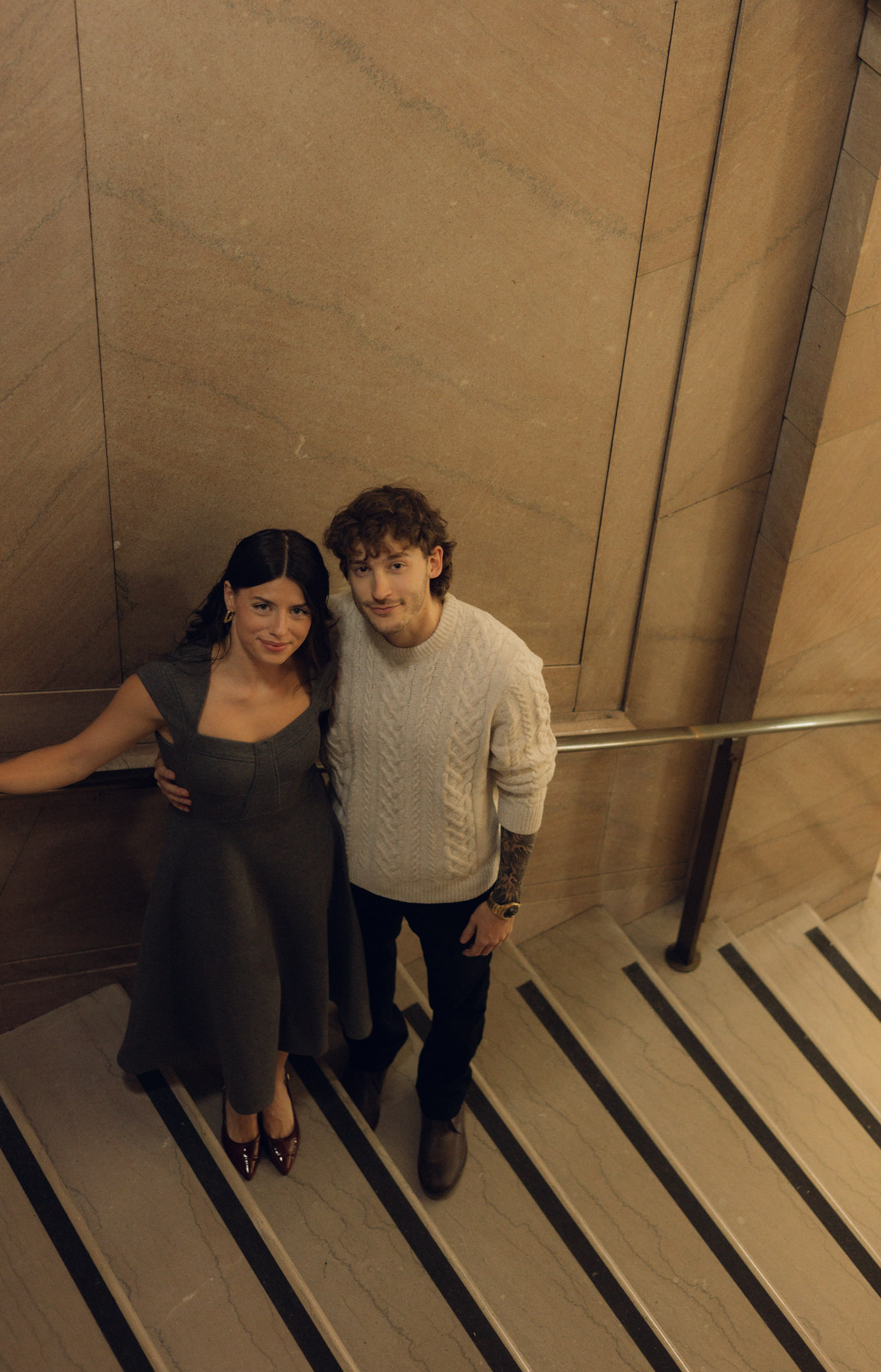 A view looking down on a couple standing on a staircase with a cinematic photography style.