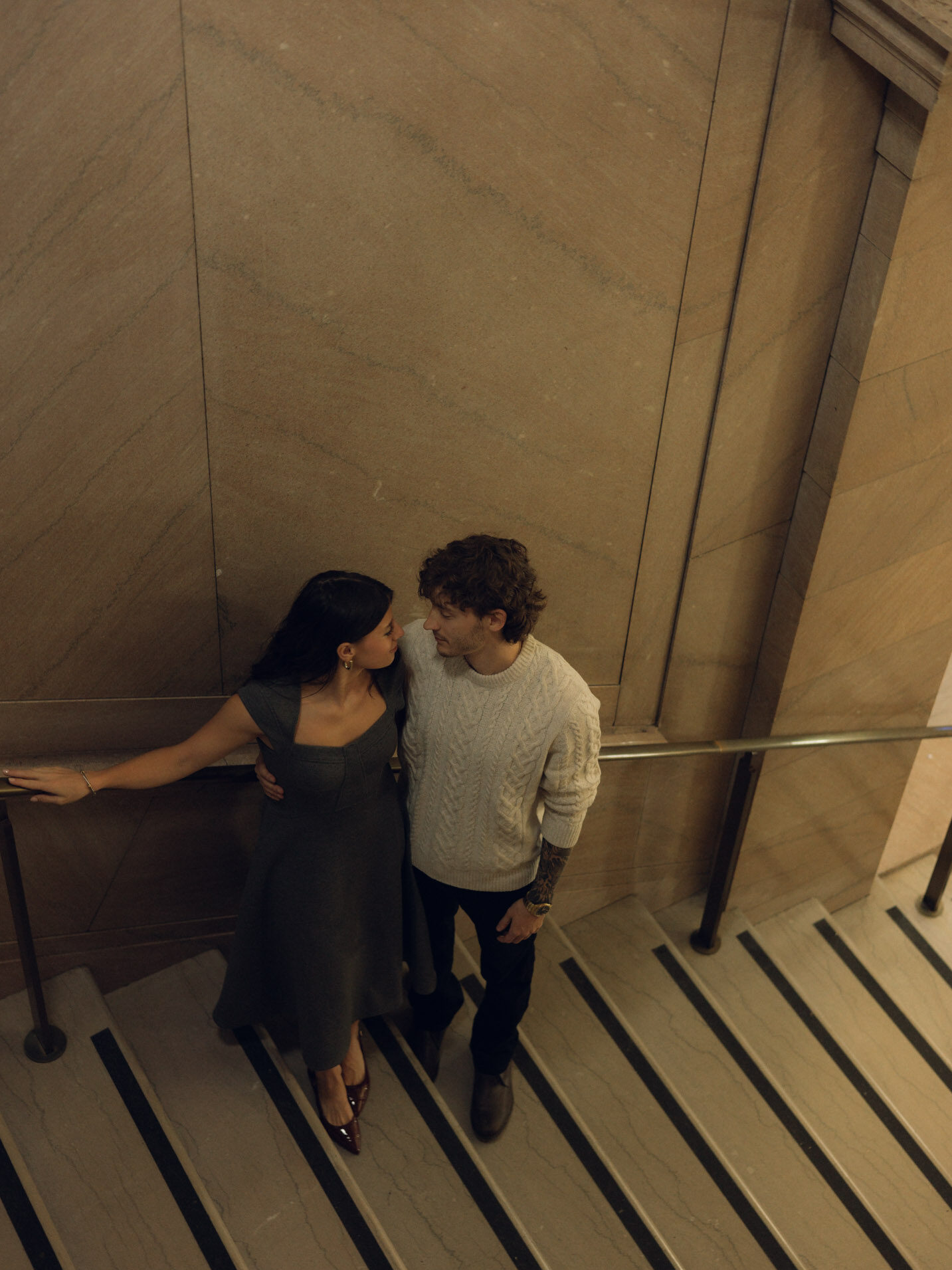 A view looking down on a couple standing on a staircase with a cinematic photography style.