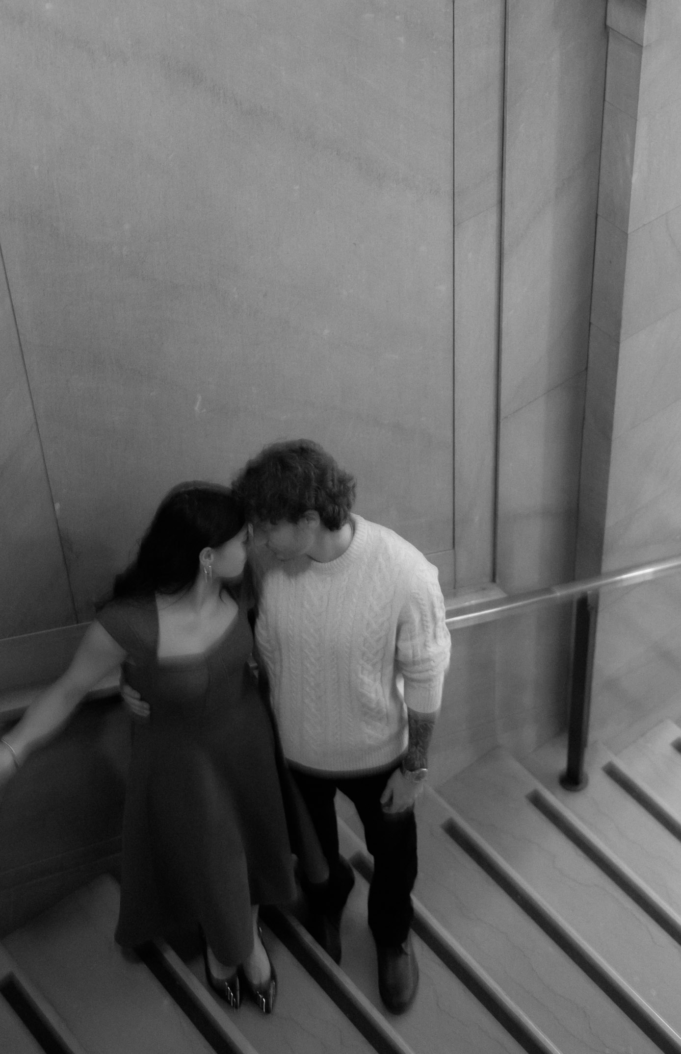 A black and white photo of a couple on a staircase.