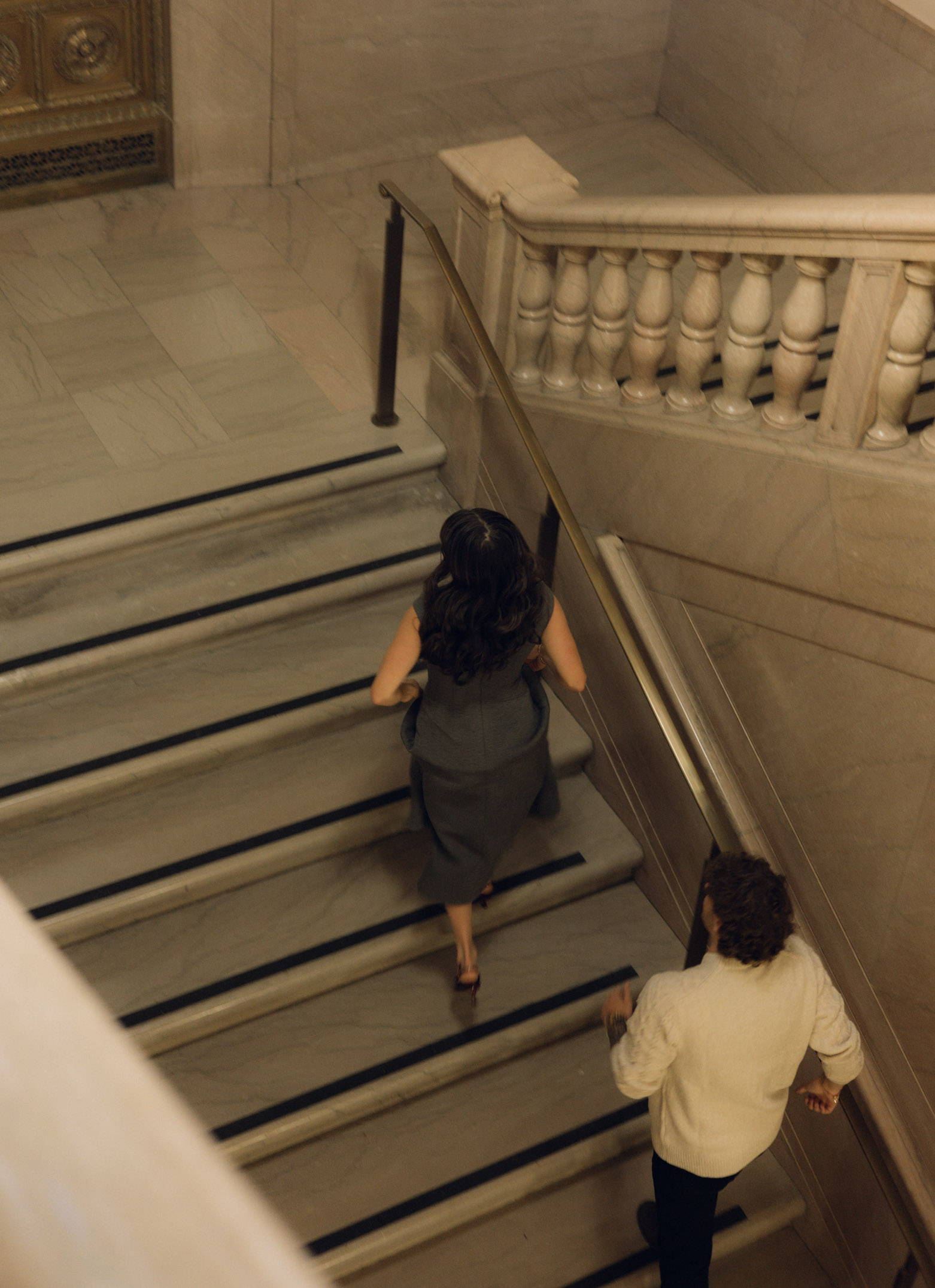 A couple runs up the stairs of a historic building.