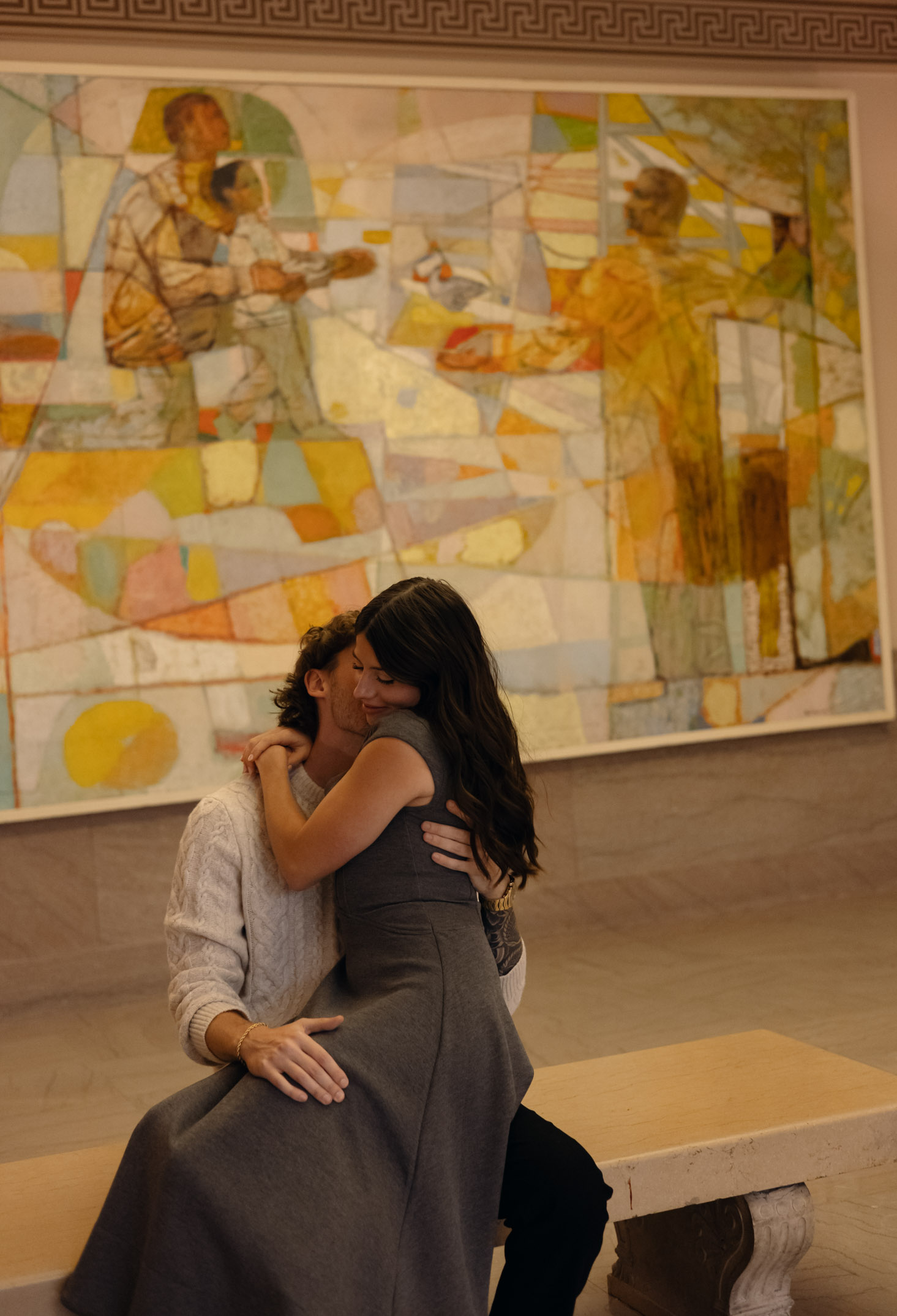 A couple embraces intimately in a museum.