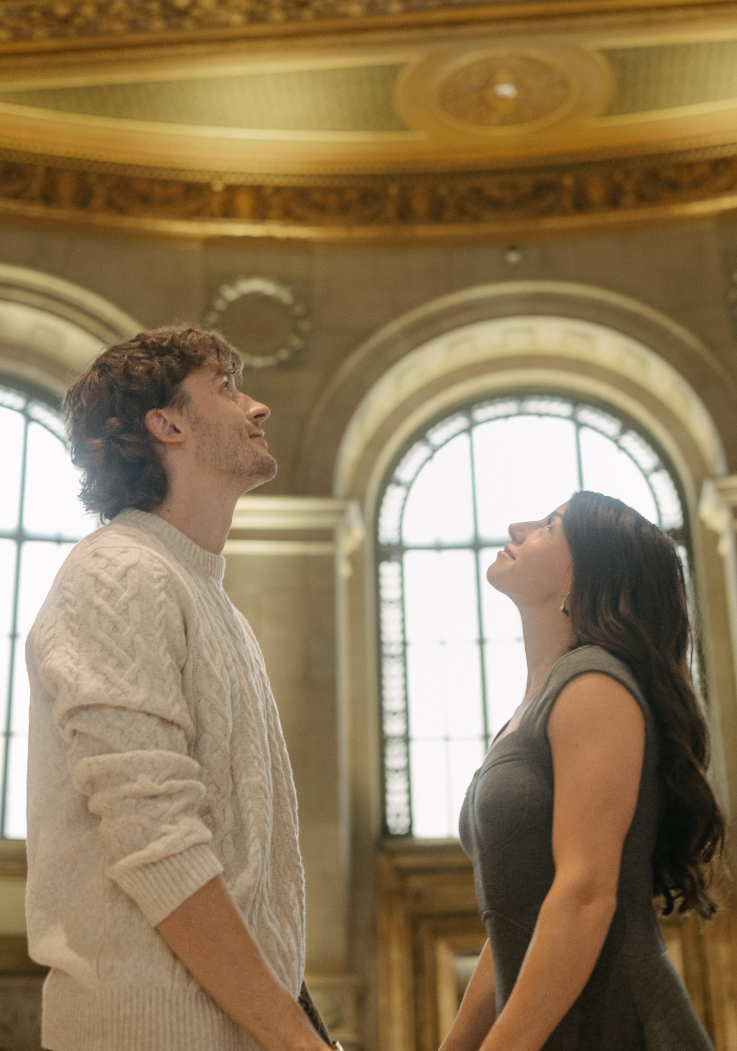 A couple looks up at an intricate ceiling during a cinematic style photoshoot.