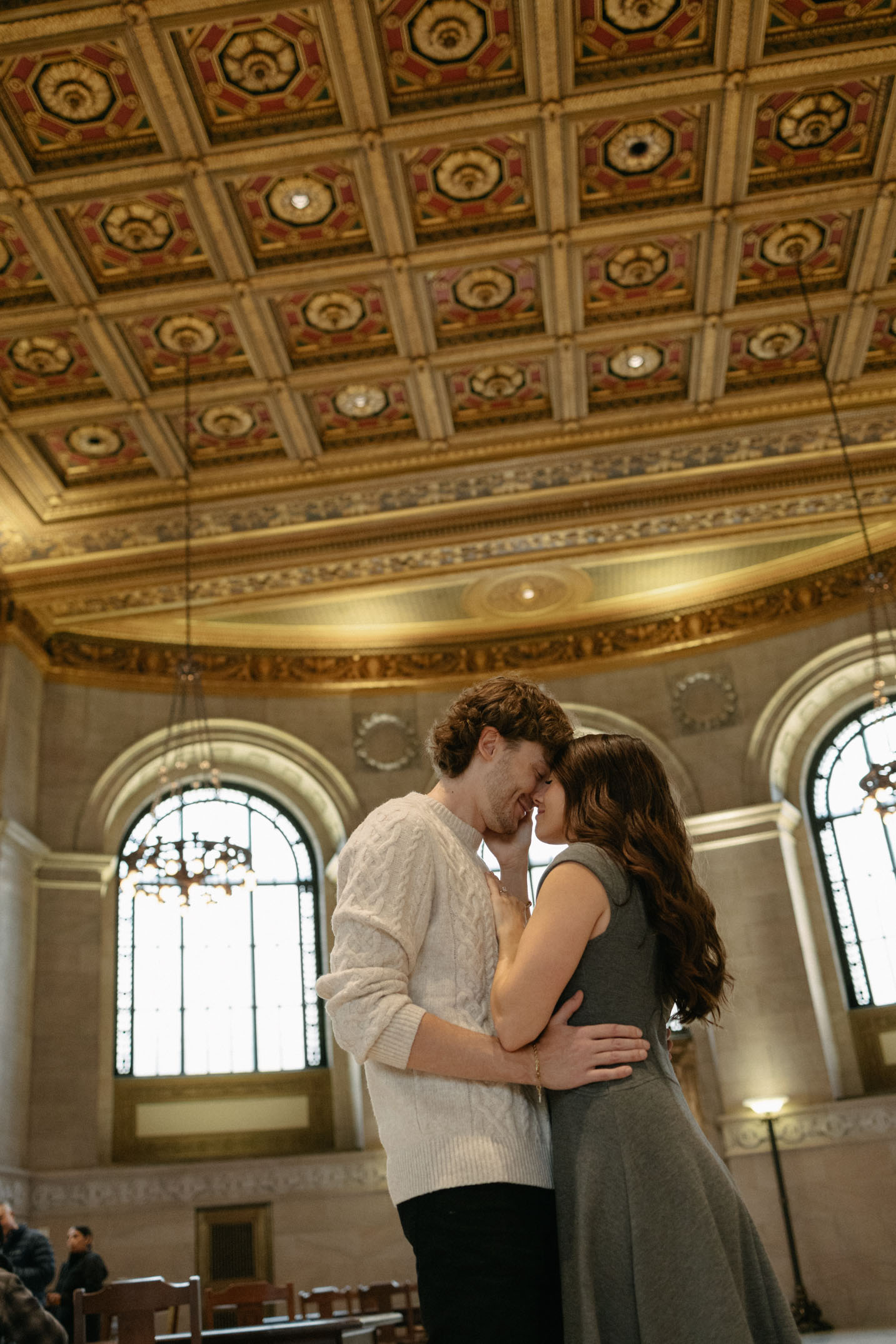 A couple embraces under an ornate ceiling of the St. Louis Public Library.