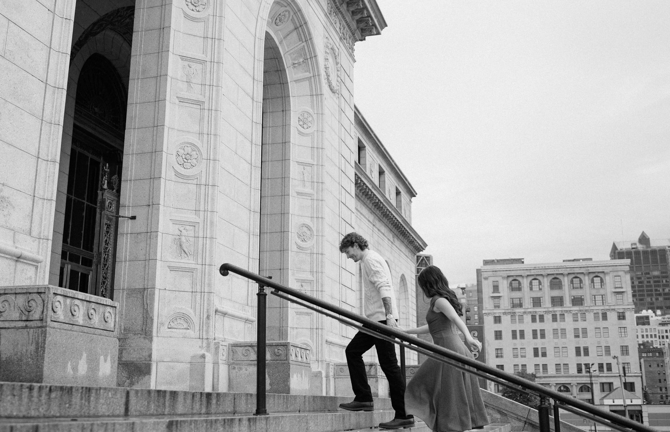 A couple runs up the steps of a downtown historic building in St. Louis, Missouri.