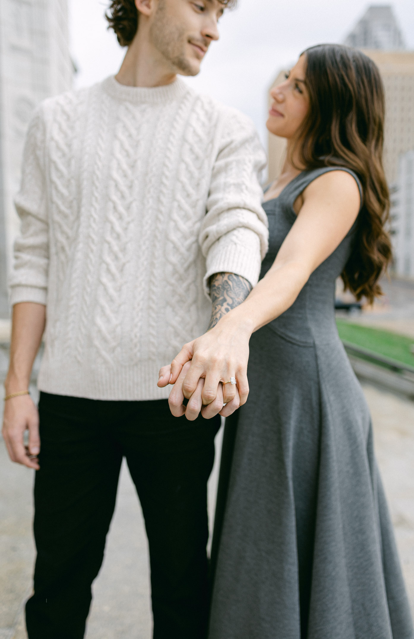 A couple holds hands and shows off an engagement ring.