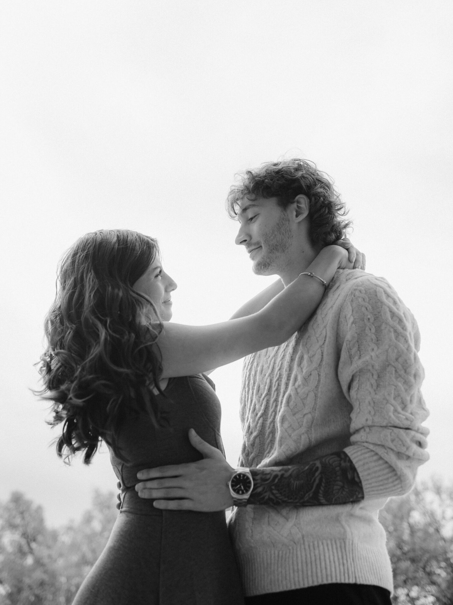 A filmy black and white photograph of a couple standing outside on a cloudy day.