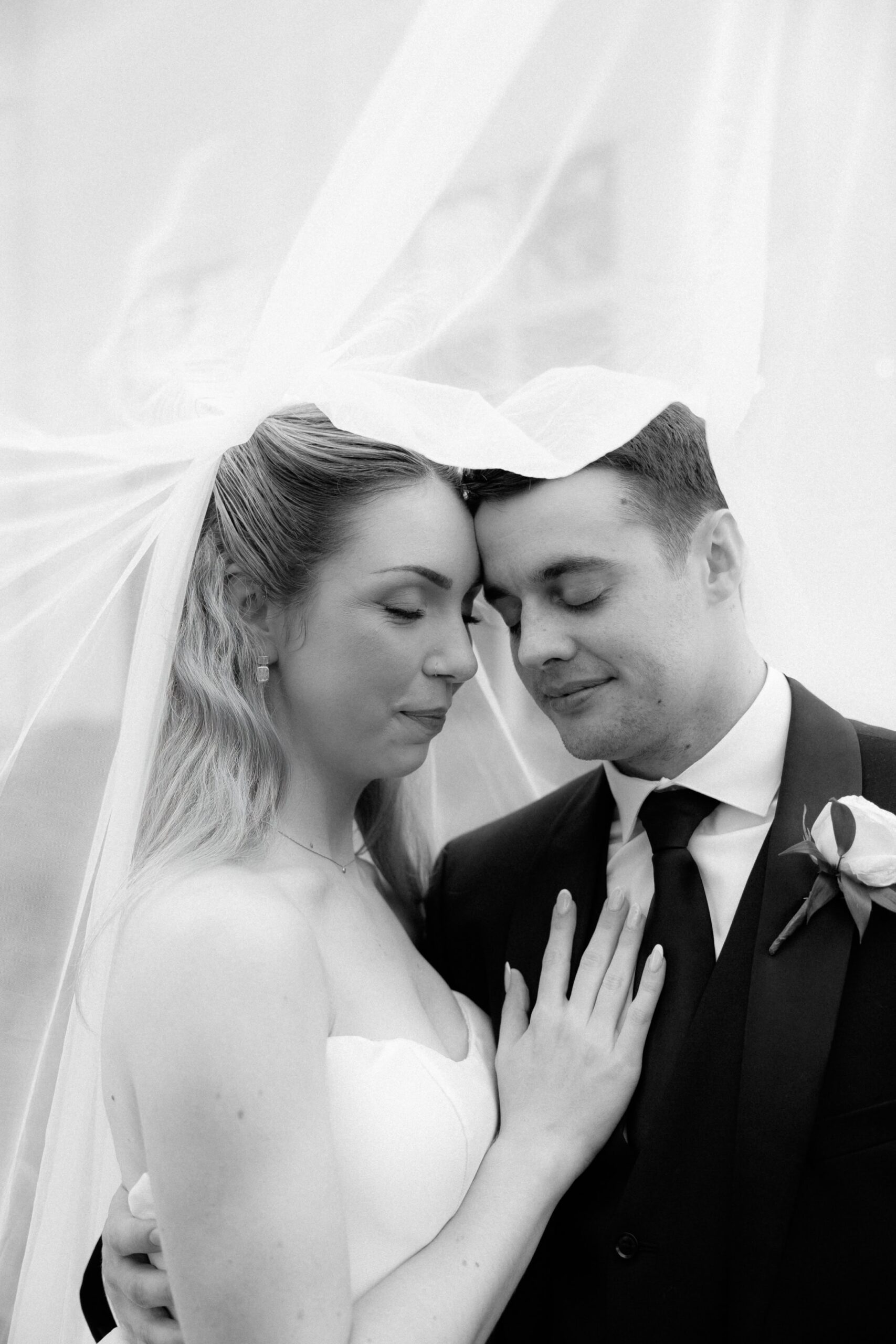 Bride and groom underneath the bride's veil.