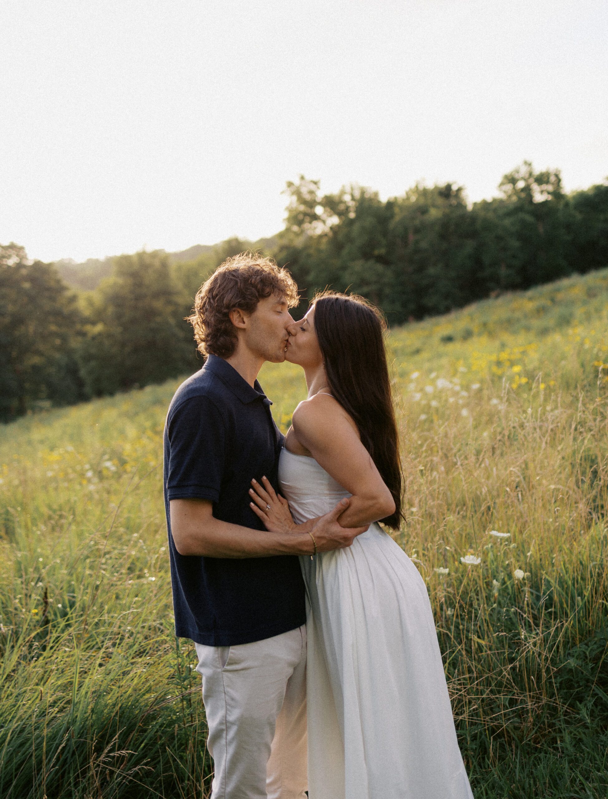a couple kisses in a wildflower field at sunset