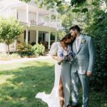 Bride and groom embrace under shady trees in a backyard wedding.