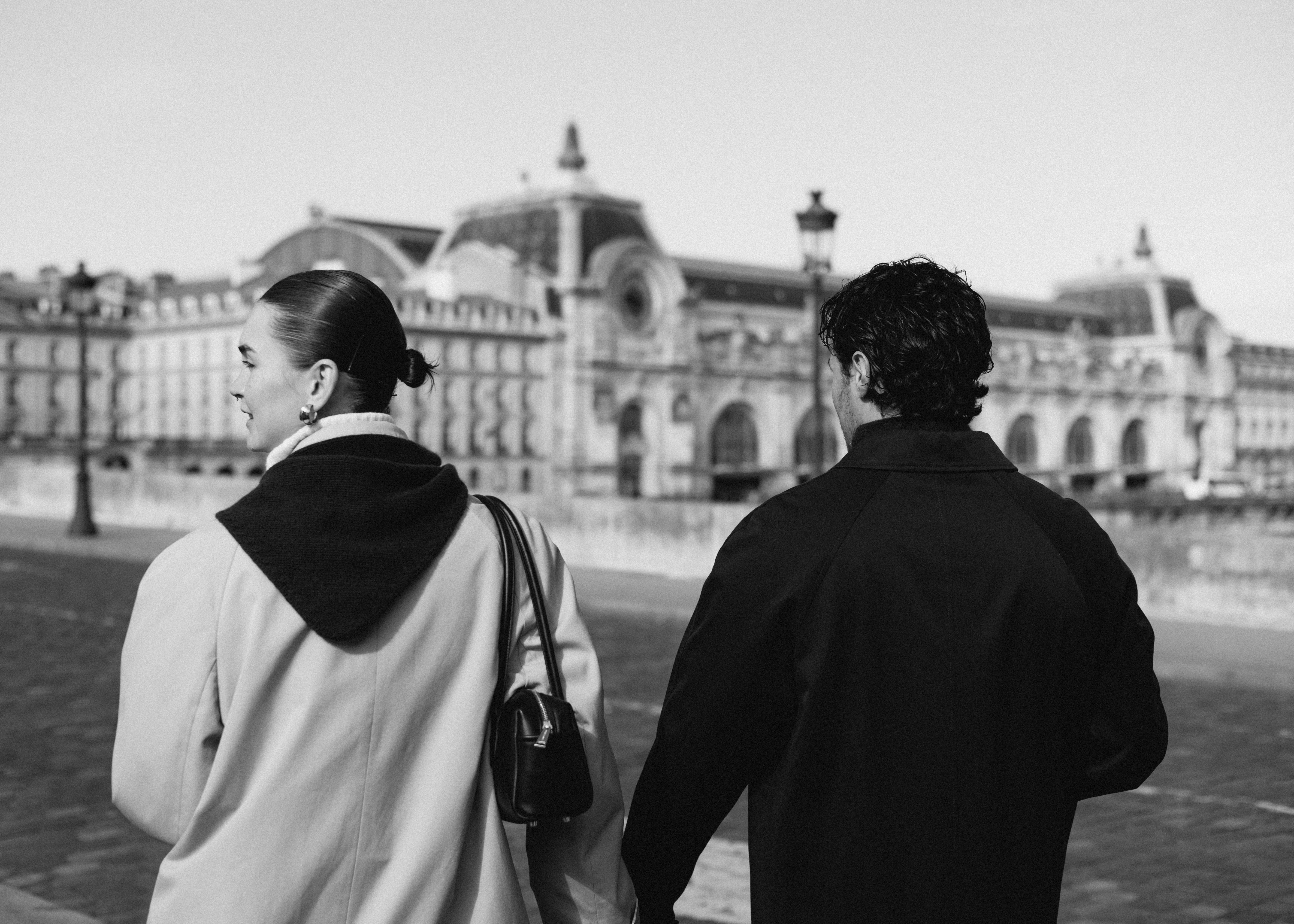 Two people walking away in front of a grand historic building, urban street scene.